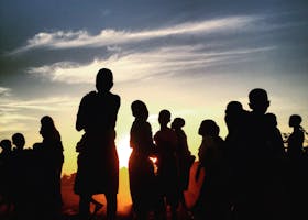 Silhouettes of a group of people against a vibrant sunset sky in Lilongwe, Malawi.